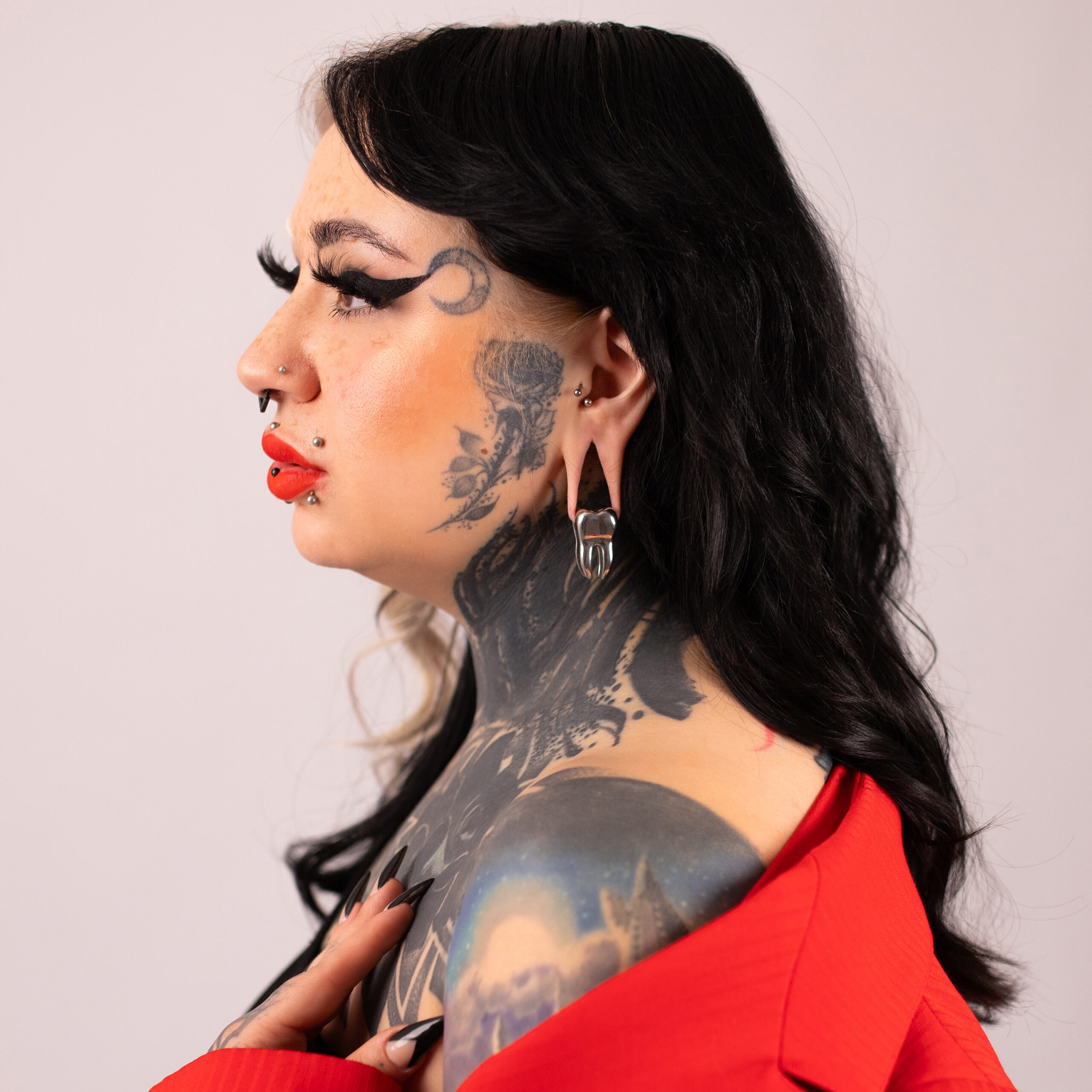 Verena Venus Ohrgewicht in Schwarz und Silber Frau mit Tattoos trägt schwarzes und silbernes Ohrgewicht, rote Kleidung