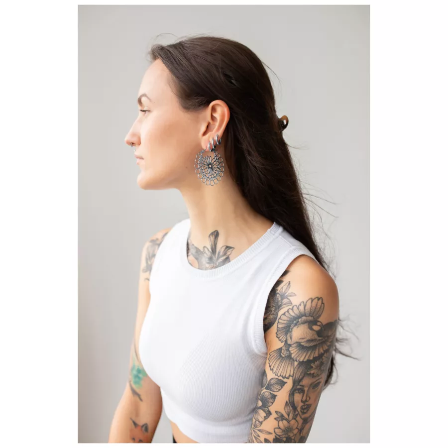 Frau mit Daisy Hoops Ohrringen in Schwarz und Silber vor grauem Hintergrund