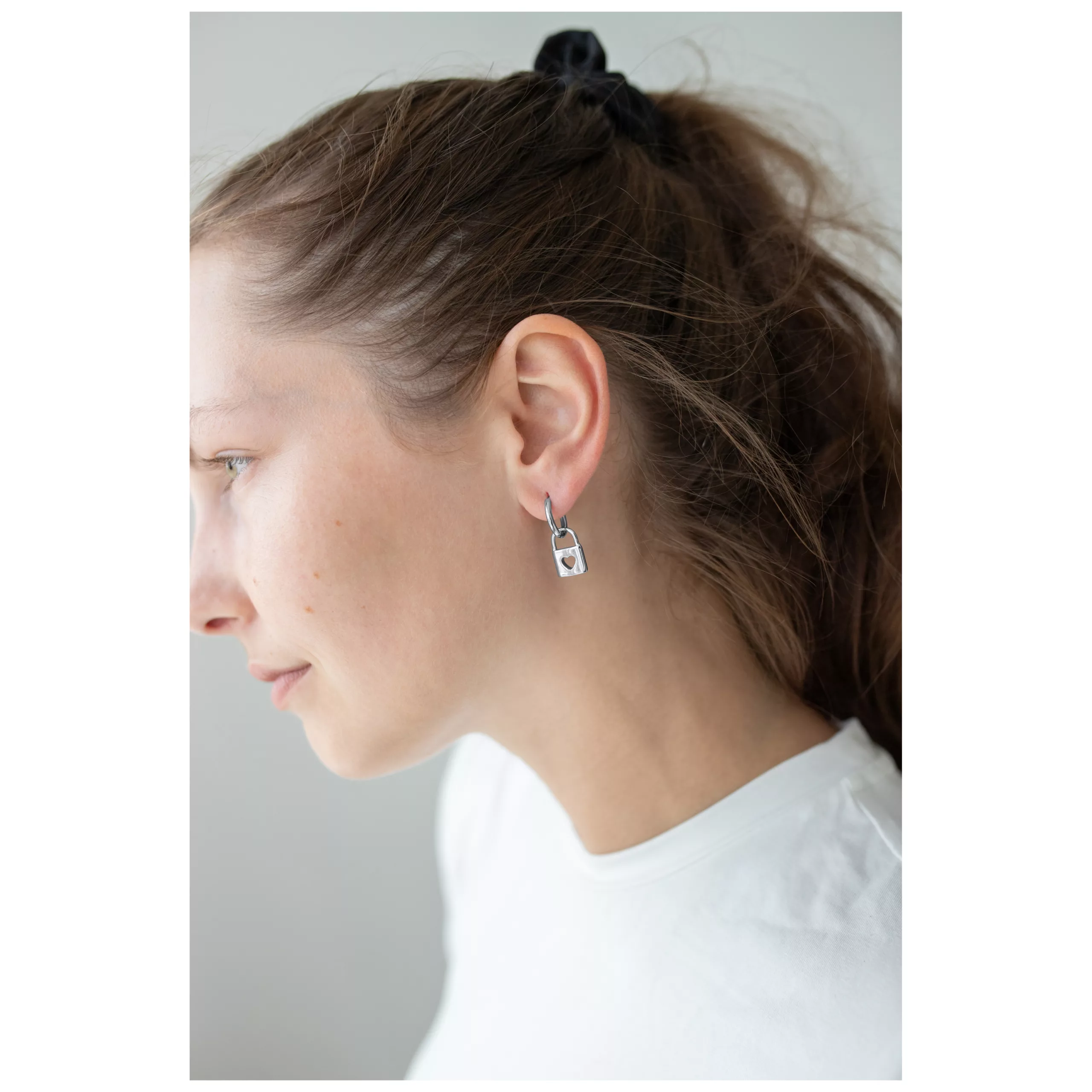 Elegante Little Lock Hoops Ohrringe in Silber Frau trägt silberne Little Lock Hoops Ohrringe vor weißem Hintergrund