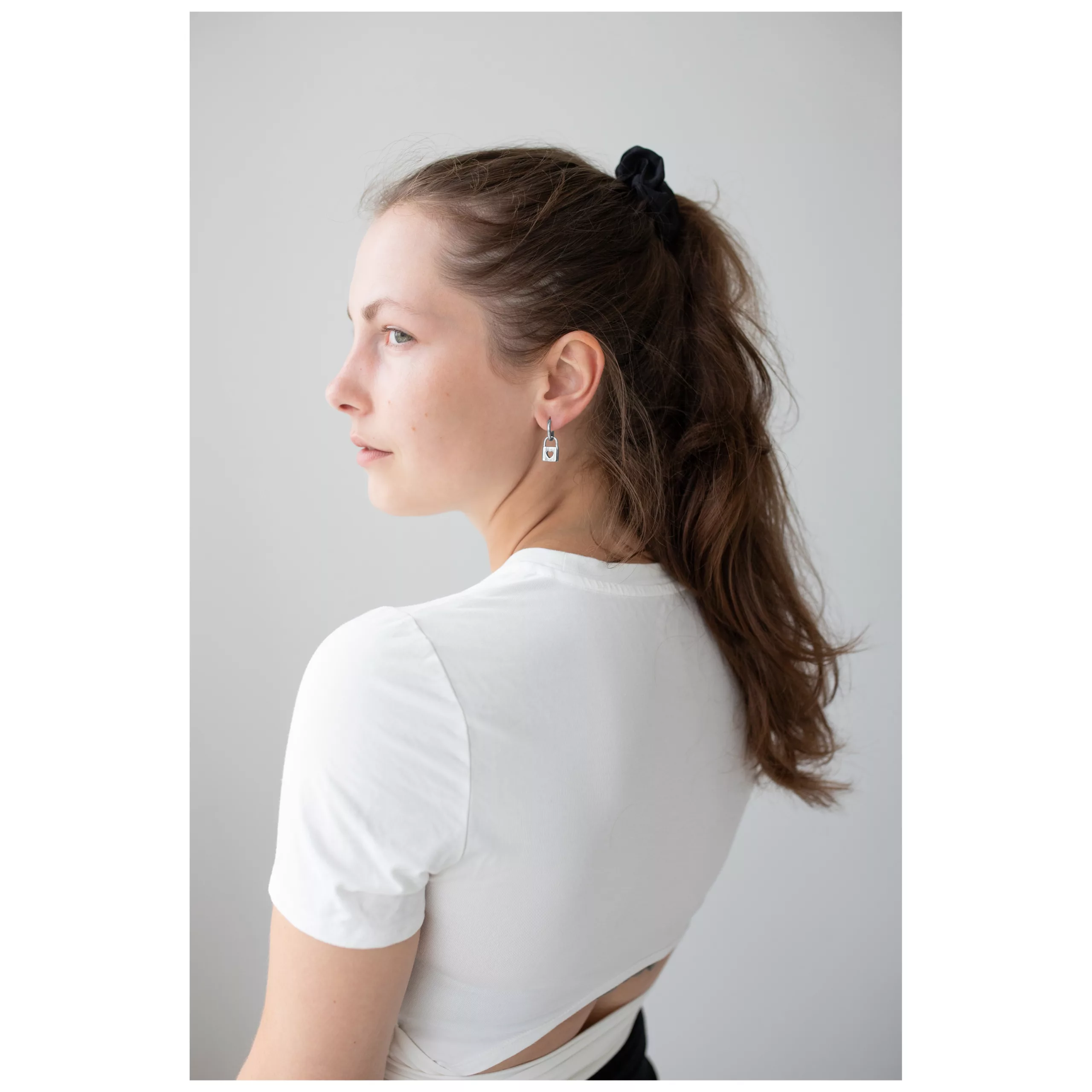 Elegante Little Lock Hoops Ohrringe in Silber Frau mit langen Haaren trägt silberne Little Lock Hoops Ohrringe vor weißem Hintergrund