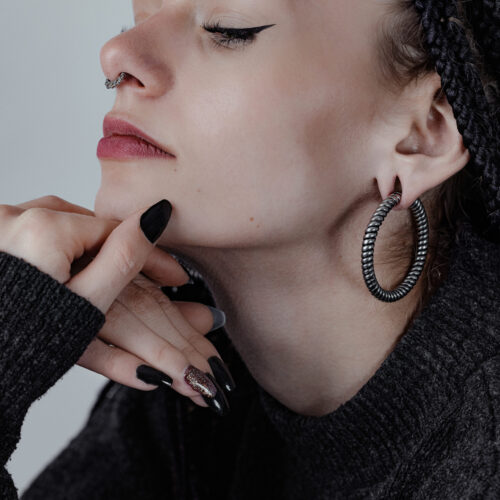 Frau mit großen, schwarzen Twisted Rope Ohrgewichten und dunklem Pullover