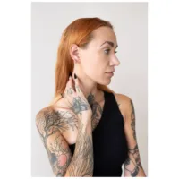 Frau mit roten Haaren trägt silberne Little Bar Hoops Ohrringe vor hellem Hintergrund