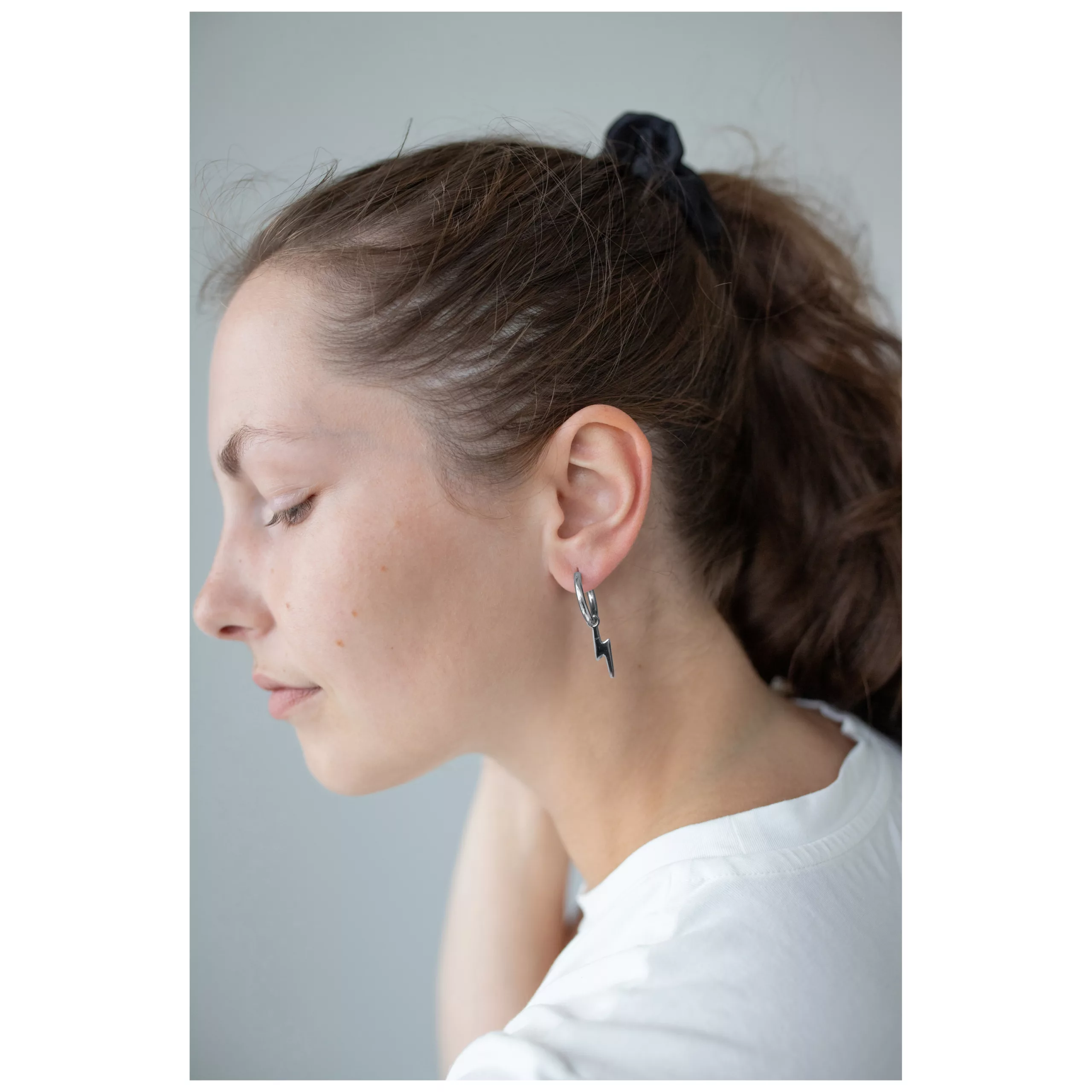 Stylische Little Flash Hoops Ohrringe Frau mit schwarzem Zopf trägt Little Flash Hoops Ohrringe aus Chirurgenstahl
