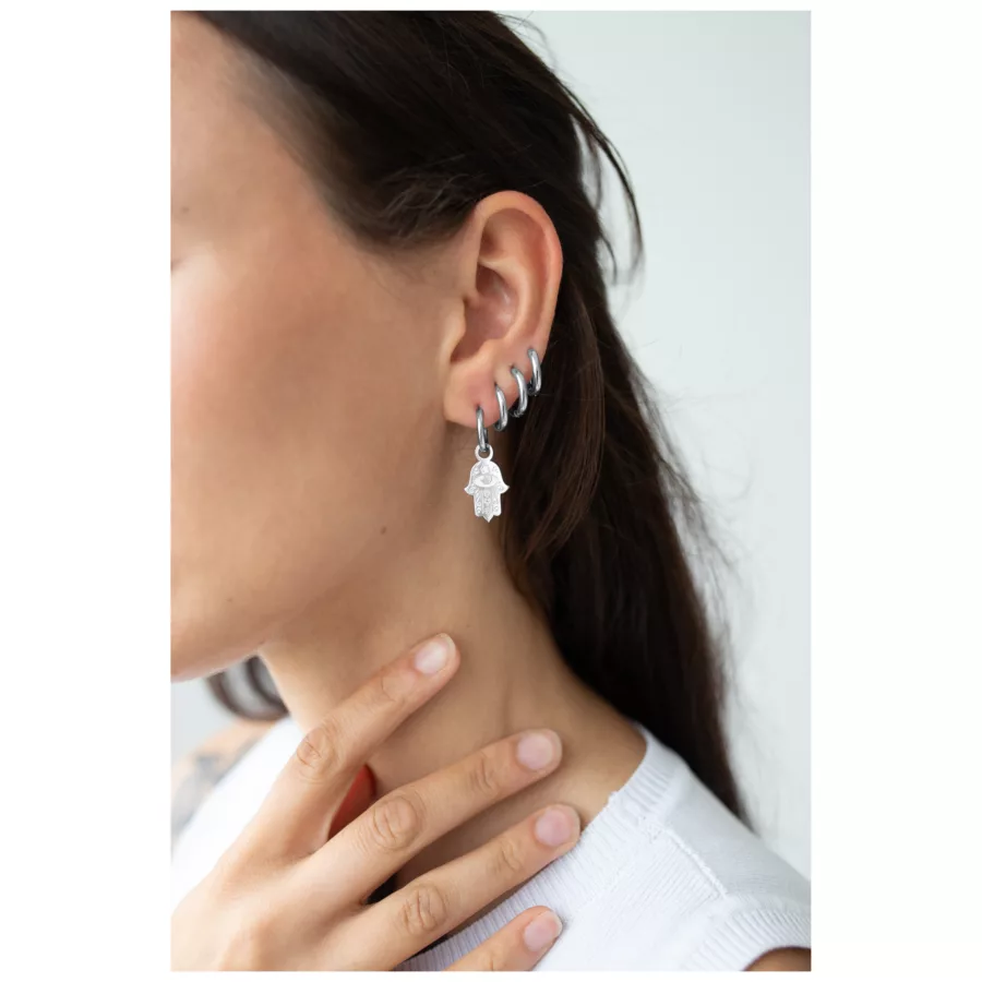 Nahaufnahme einer Frau mit silbernen Little Hamsa Hand Hoops Ohrringen, die ihr Ohr schmücken