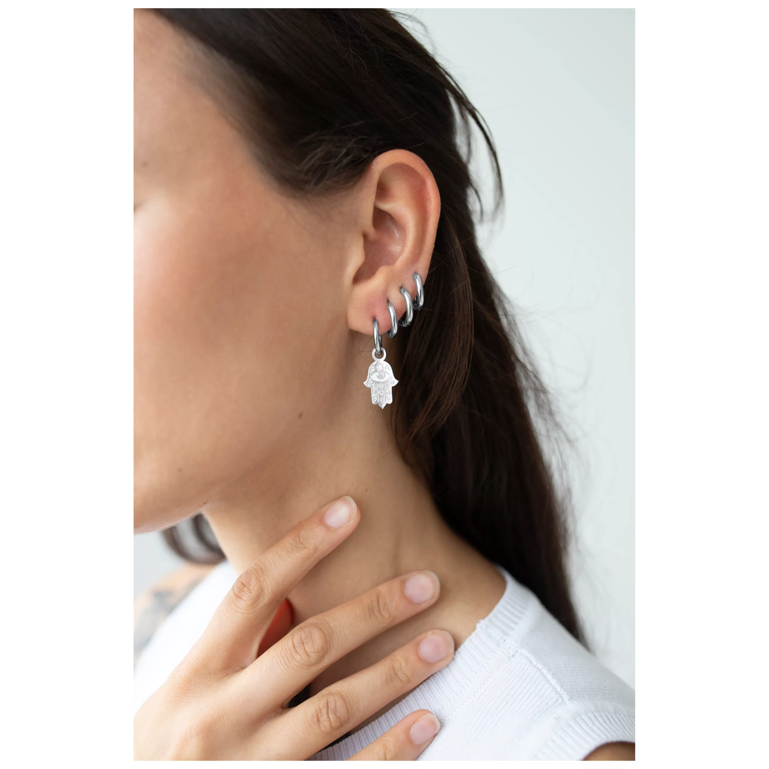 Elegante Little Hamsa Hand Hoops Ohrringe Nahaufnahme einer Frau mit silbernen Little Hamsa Hand Hoops Ohrringen, die ihr Ohr schmücken
