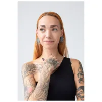 Frau mit roten Haaren trägt silberne Mandala Ohrringe, Tattoos sichtbar