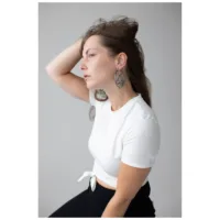 Frau mit Lotus Hoops Ohrringen aus Edelstahl in Schwarz und Silber auf grauem Hintergrund