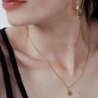 Goldene Little Sunflower Kette für Damen Dame mit goldener Little Sunflower Kette, filigran und elegant, auf hellem Hintergrund