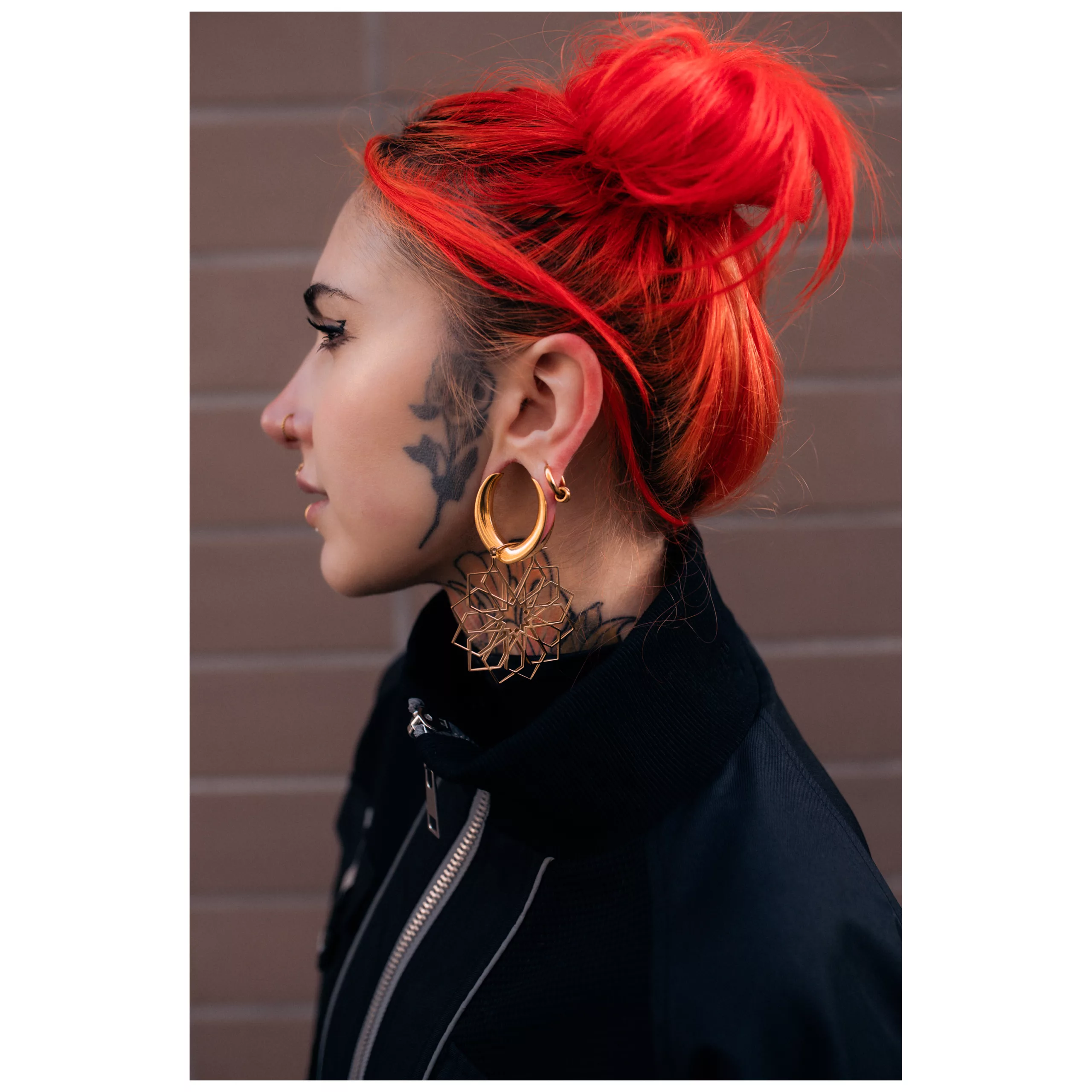 Kaleidoscope Hoops in Gold getragen Frau mit roten Haaren trägt goldene Kaleidoscope Hoops vor einer Backsteinwand