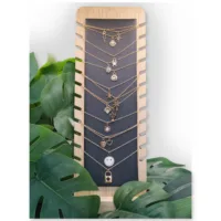 Schwarzes Schmuckdisplay aus Kunstleder und Holz Schwarzes Display aus Kunstleder und Holz mit Ketten und Pflanzen im Hintergrund