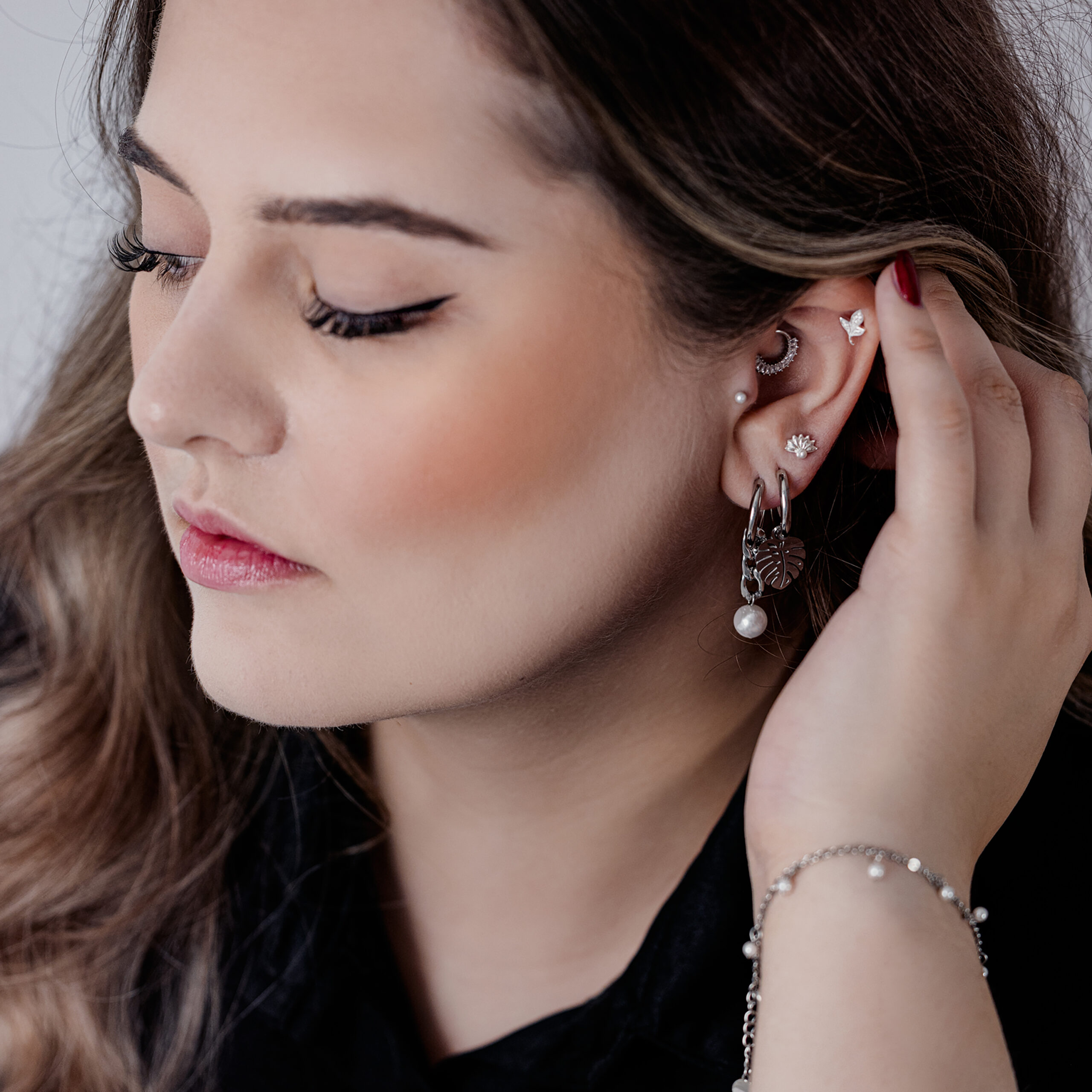 Frau mit eleganten schwarzen und silbernen Chunky Pearl Hoops und anderen Ohrpiercings