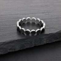 Silberner Plate-Ring aus Chirurgenstahl Silberner Ring aus Chirurgenstahl auf dunkler Steinoberfläche