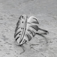 Silberner Monstera Blatt Ring aus Chirurgenstahl auf grauem Hintergrund