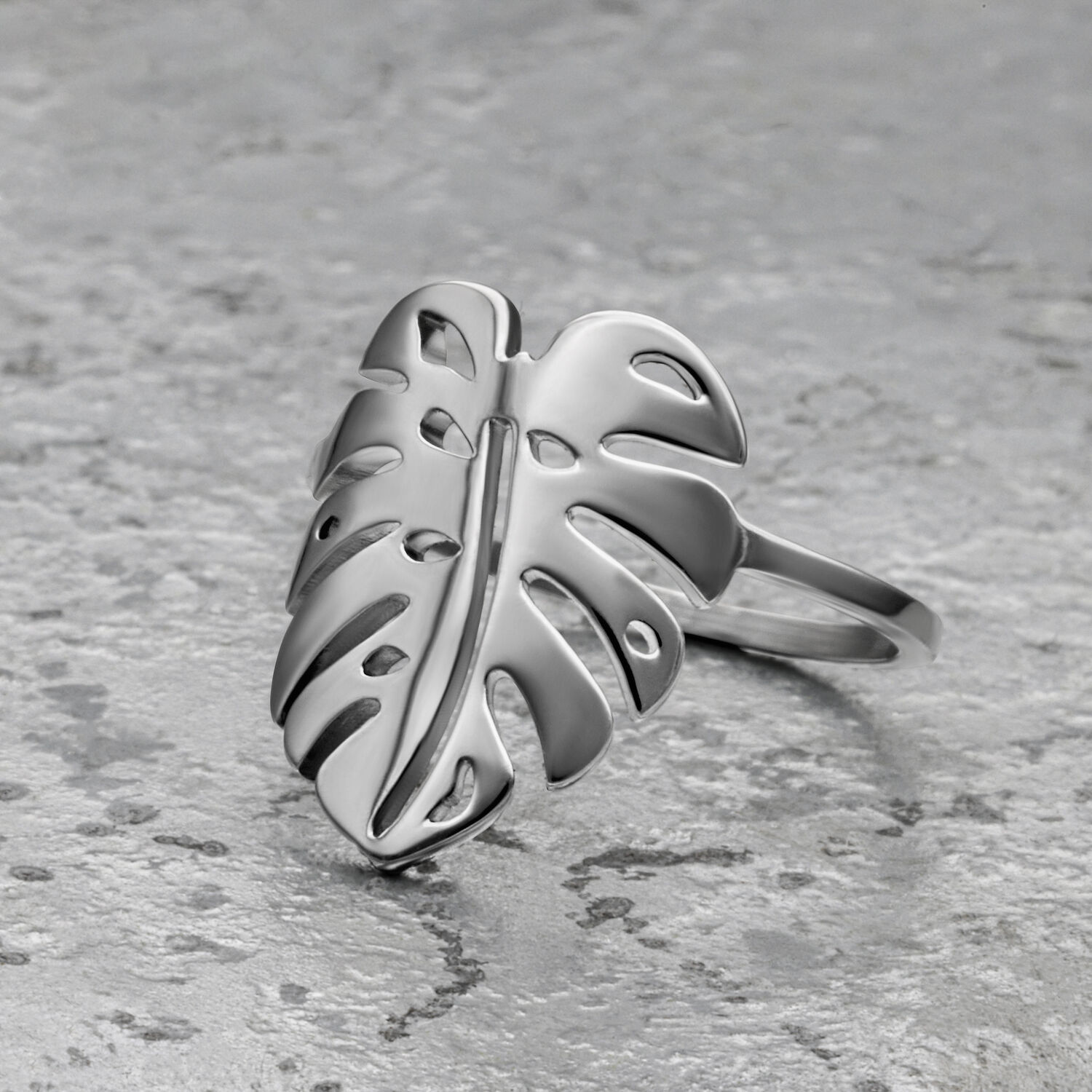 Silberner Monstera Blatt Ring aus Chirurgenstahl auf grauem Hintergrund