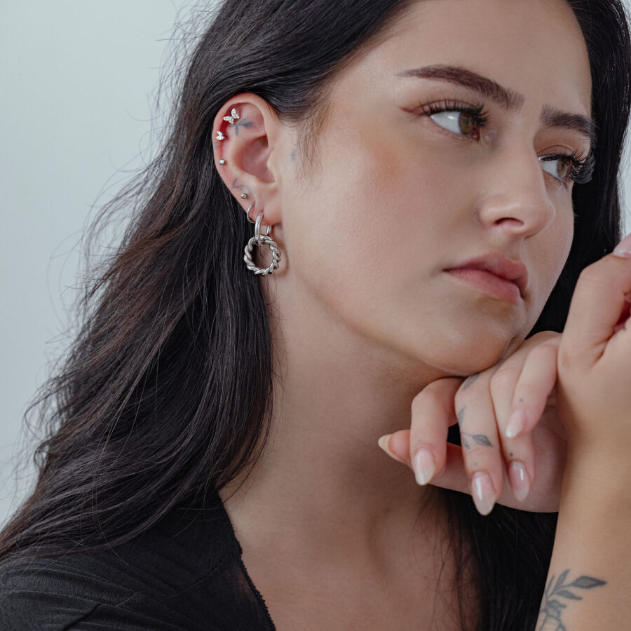 Frau mit langen Haaren trägt silberne Twisted Circle Hoops, seitliches Profil