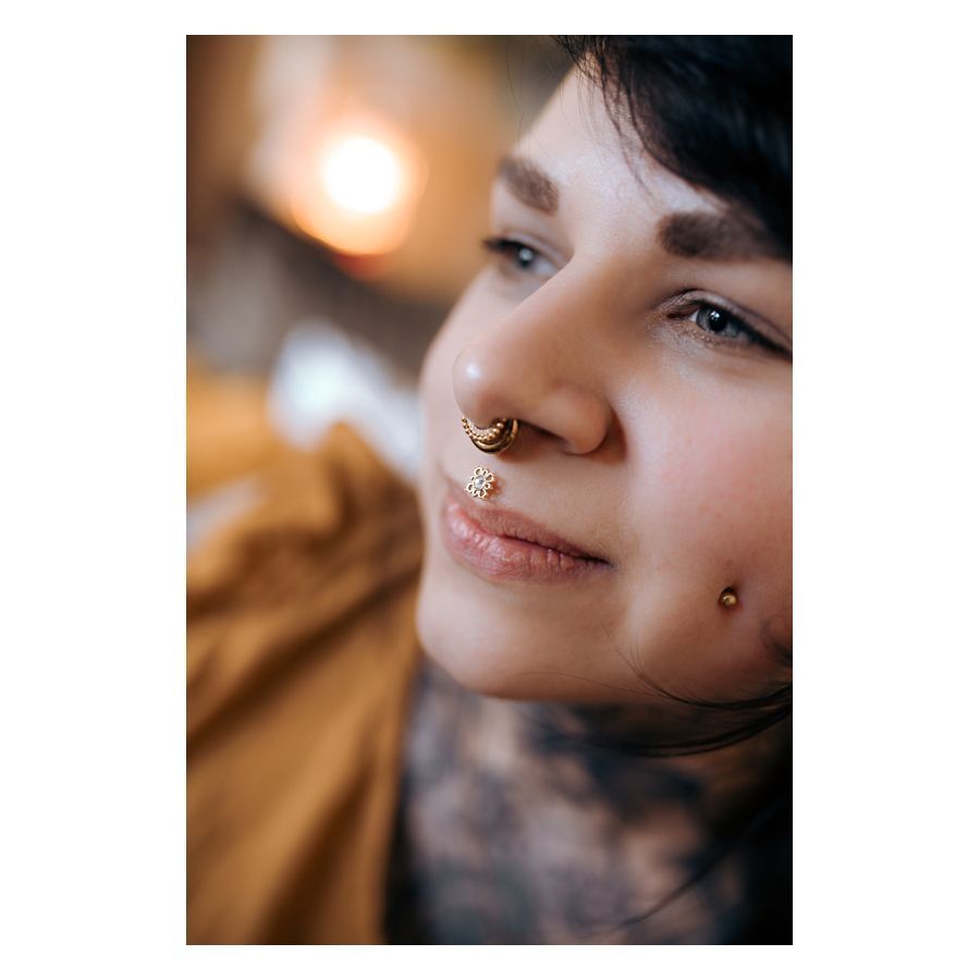 Nahaufnahme einer Person mit Oriental Sun Push-Fit Labret im Nasenpiercing, goldene Farbe