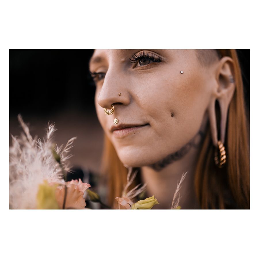 Stylishes Flower Push-Fit Labret im Ohr Frau mit Flower Push-Fit Labret im Ohr, umgeben von Blumen, im Freien